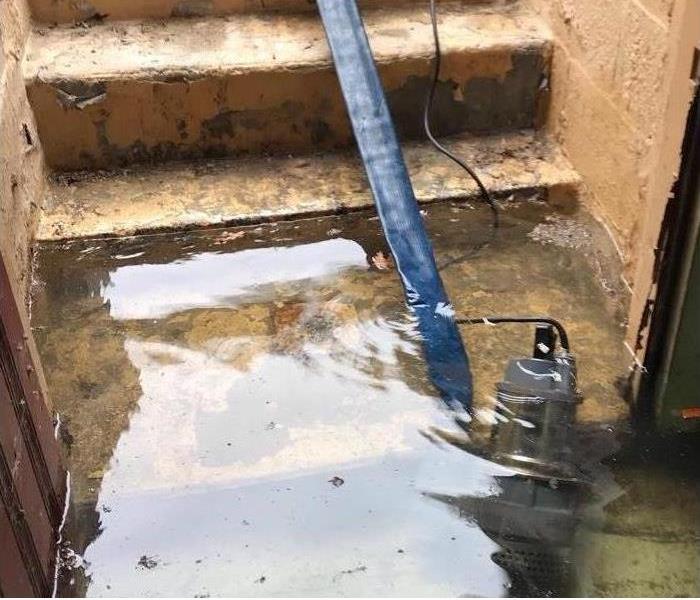 a submersible pump, blue hose, at flooded basement stairs
