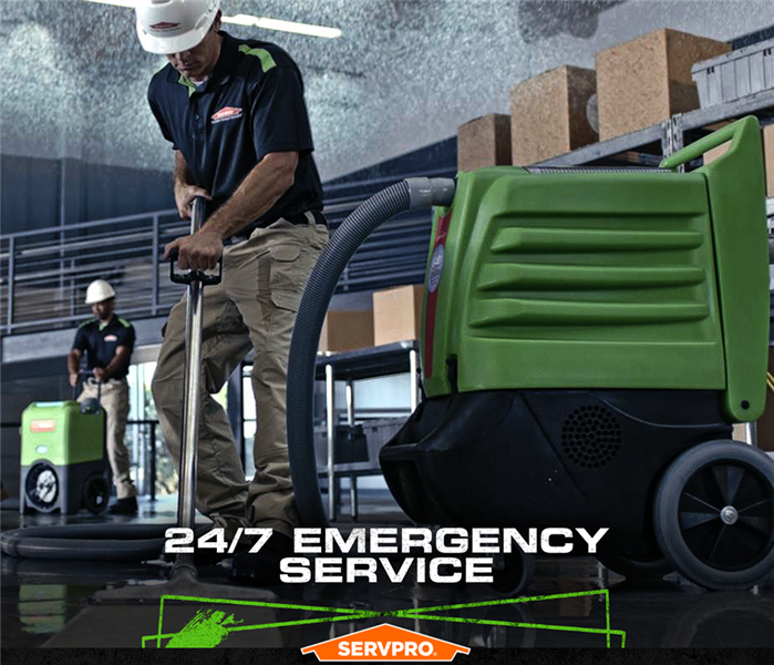 SERVPRO crew extracting water from a flooded building with the caption: "24/7 Emergency Service"